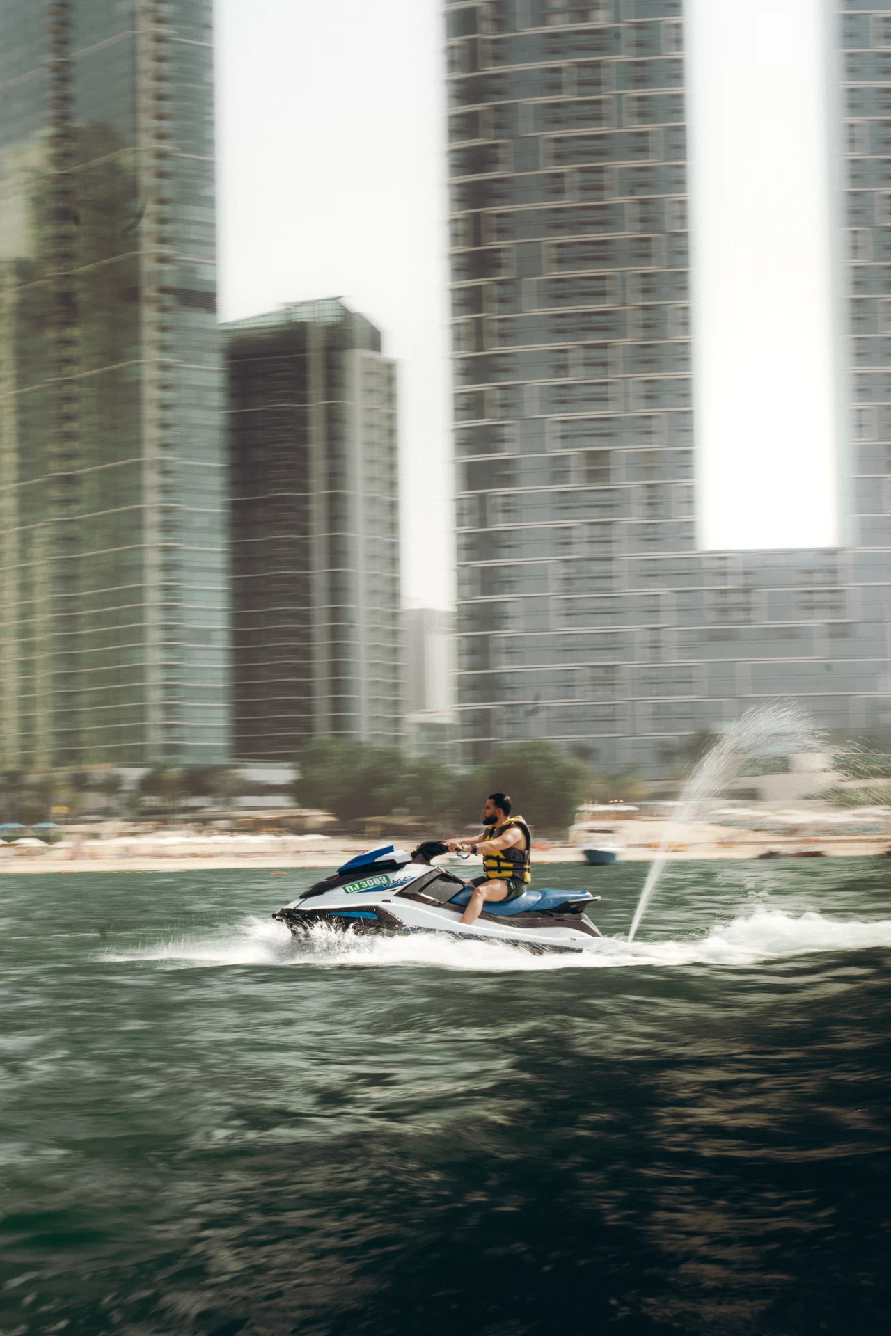 Zack Lalouti riding a jet ski across the water in front of high-rise buildings in Dubai.