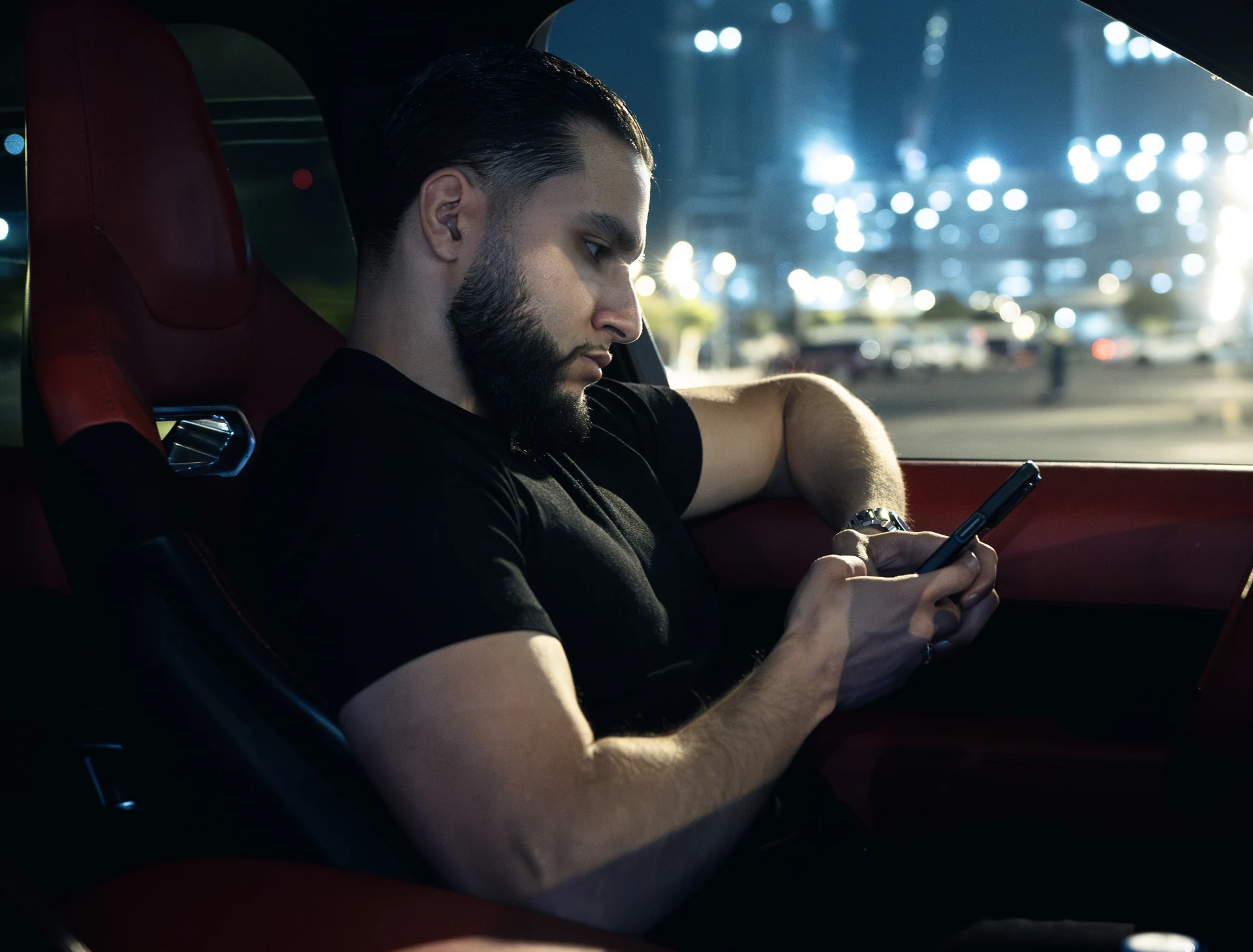 Zack Lalouti using his smartphone while seated in a car at night.