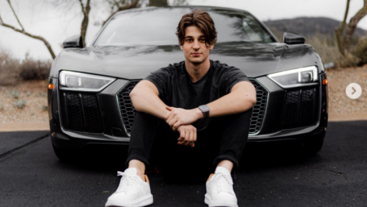 Sebastian Ghiorghiu seated in front of a car.