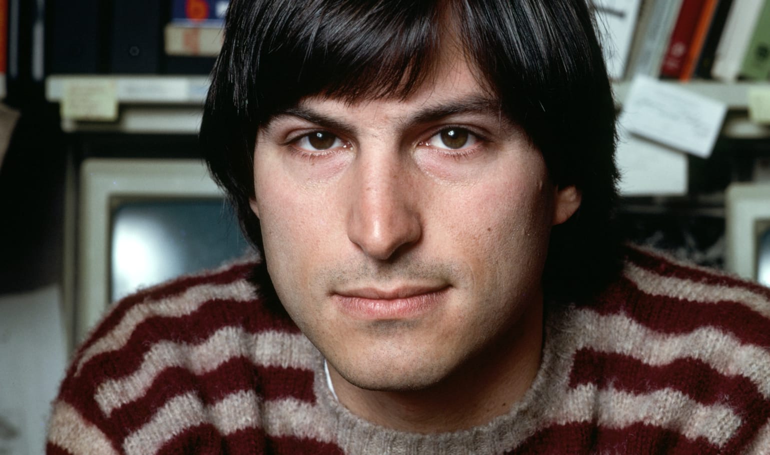 Steve in 1984, clean shaven and wearing a wool sweater with maroon stripes, gazes into the camera. Photograph by Norman Seeff.