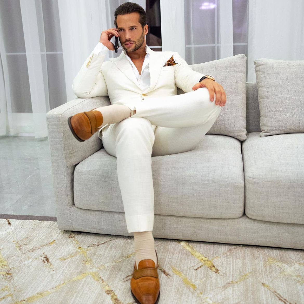 Tristan Tate seated in a white suit.
